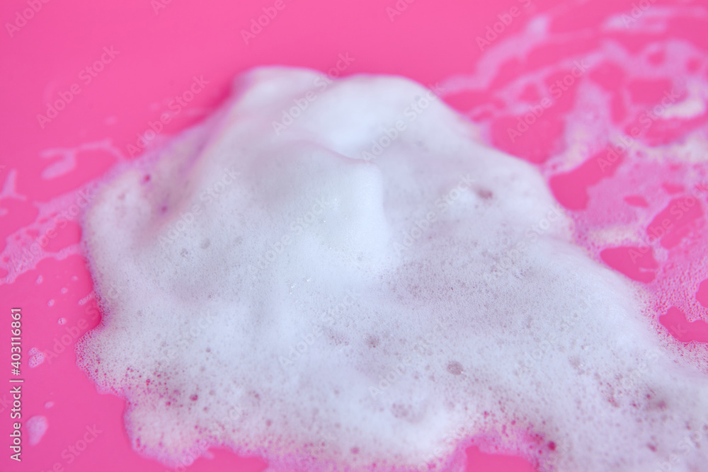 Foam bubbles and brick of soap on pink background. White foam snear from soap, shampoo or cleanser on pink background with selective focus Cleaning service
