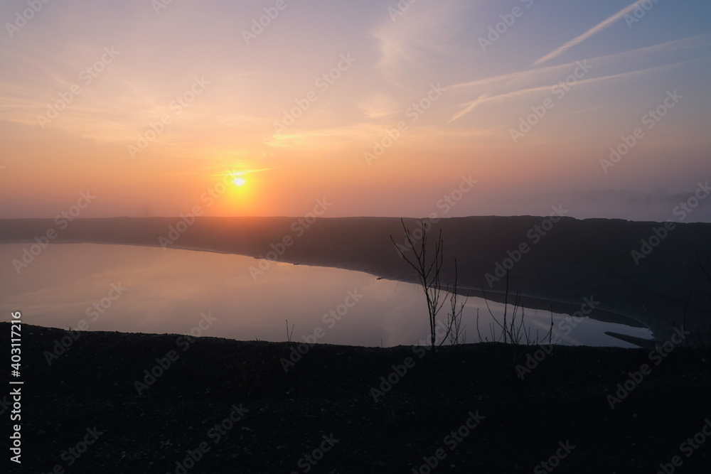 Fototapeta premium Wschód słońca we mgle nad wodą