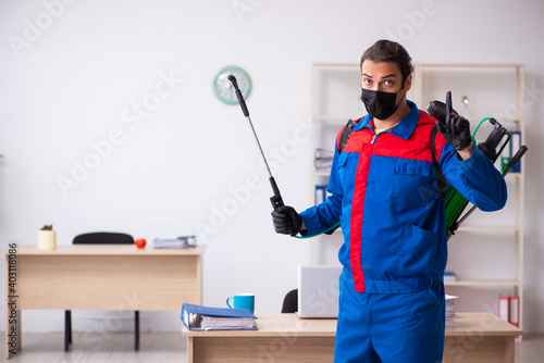 Young male contractor disinfecting office