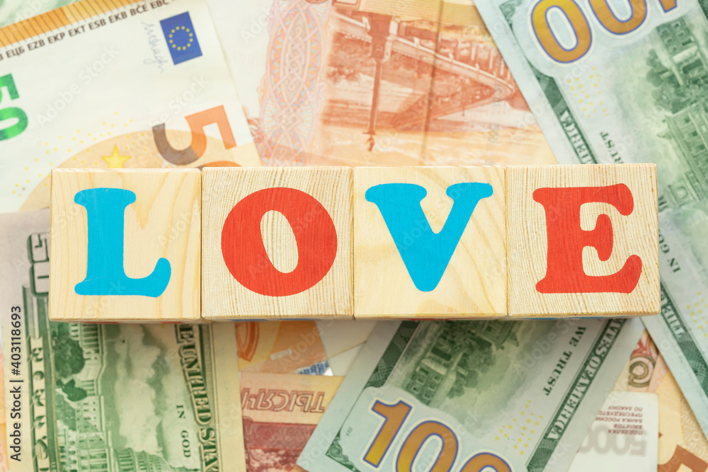 Multicolored cubes inscription love on the background of bills dollars euros rubles Multicolored cubes inscription love on the background of bills dollars euros rubles