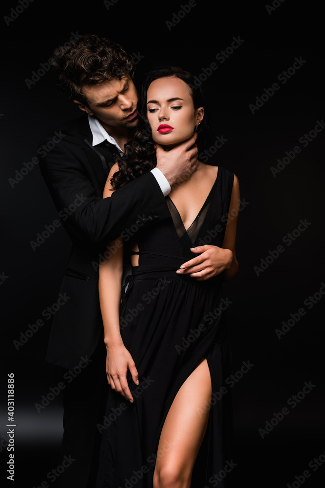 passionate man choking sexy and submissive woman in dress on black