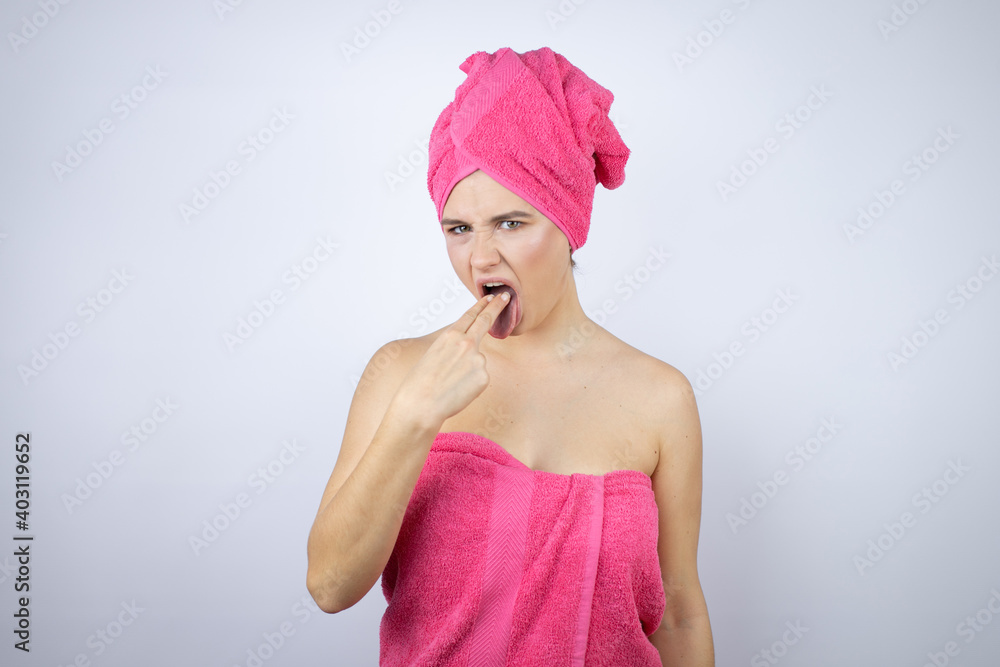 Young beautiful woman wearing shower towel after bath standing over isolated white background disgusted with her hand inside her mouth Young beautiful woman wearing shower towel after bath standing over isolated white background disgusted with her hand inside her mouth