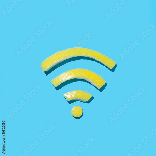 Wifi symbol concept with bright yellow lemon peel cut into Wireless internet shape on a cyan blue background. Minimal flat lay