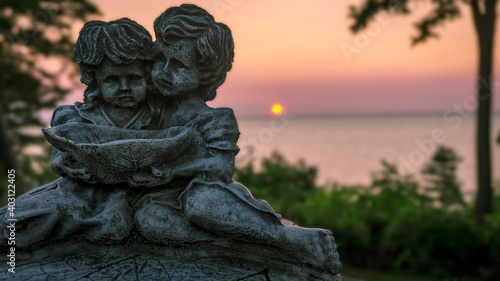 A photo of a statue with the sun setting on the horizon © Dan's Photos
