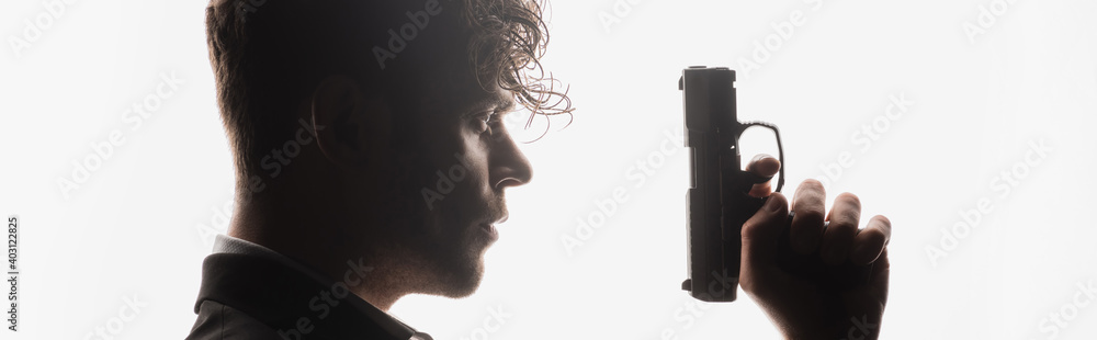 side view of curly man holding gun isolated on white, banner