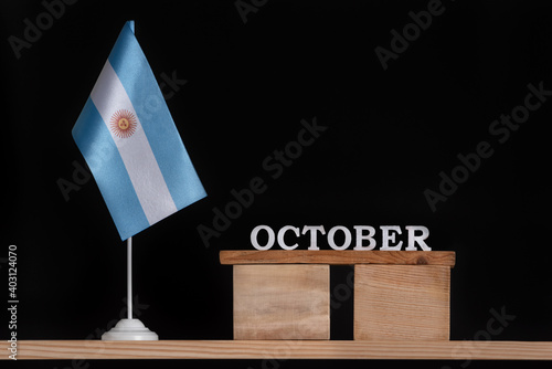 Wooden calendar of October with Argentine flag on black background. Holidays of Argentina in October