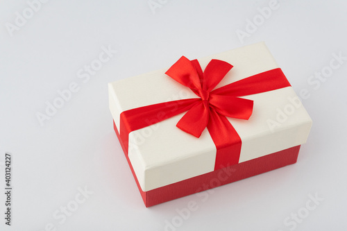 White box with red ribbon on white background. Gift wrap