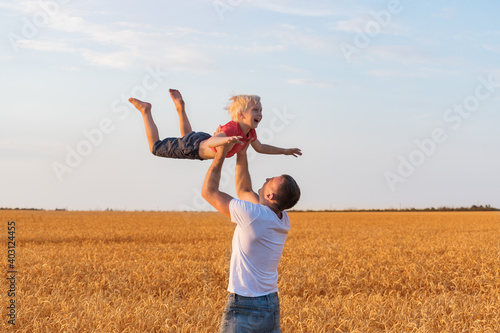 Father and child boy playing outdoors in countryside. Dad throws son. photo