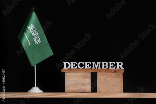 Wooden calendar of December with Saudi Arabia flag on black background. Dates of Saudi Arabia in December