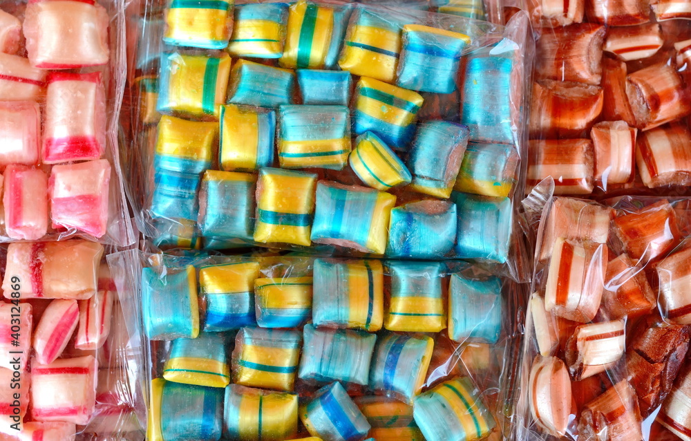 Multicolored candies in an transparent plastic wrap as a background.