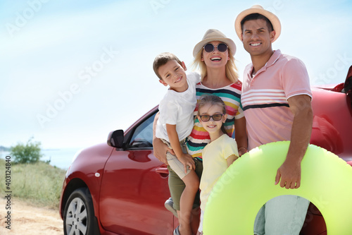 Happy family with inflatable ring near car at beach © New Africa