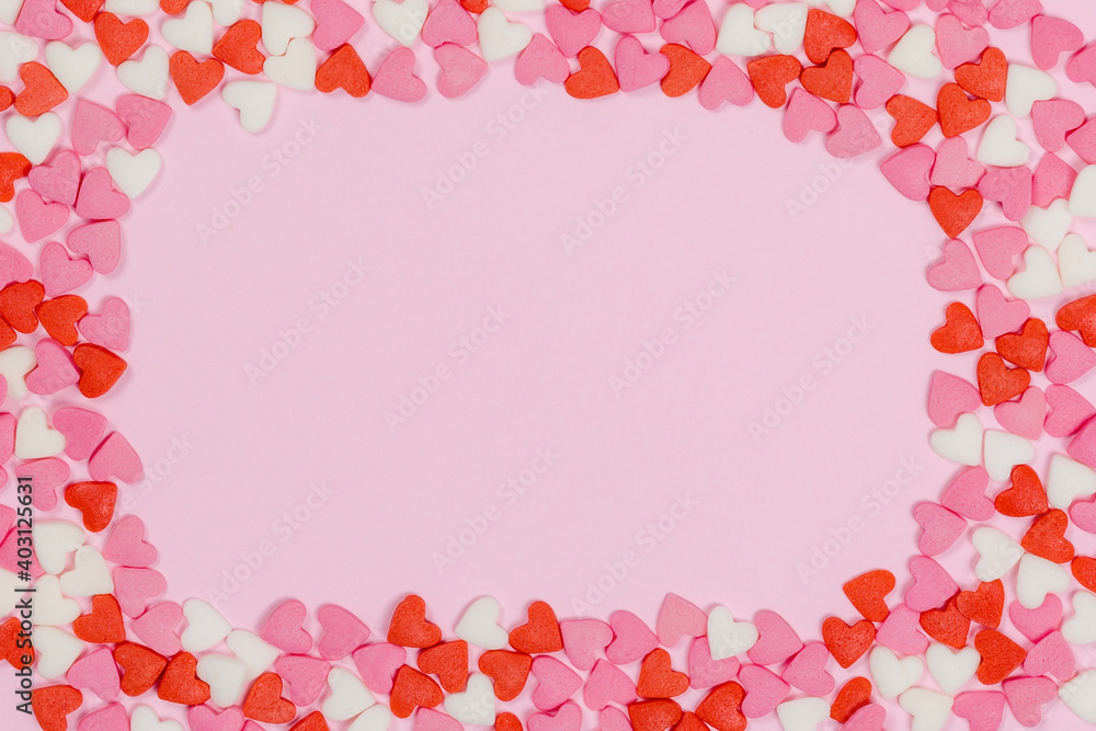 Heart shaped candies scattered on pink background