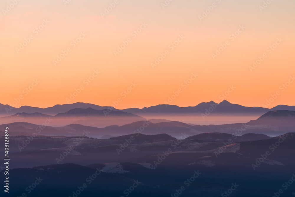 High mountain ranges in dense fog. Layers of mountains in the haze during sunset. Multi-layered foggy mountains.