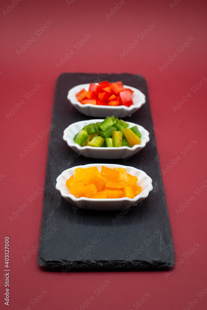 three small try-plates with green, yellow and red peppers on slate plate