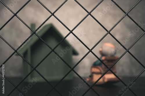 lonely old man sitting on an armchair behind the fence concept of lonely elder people or quarantine