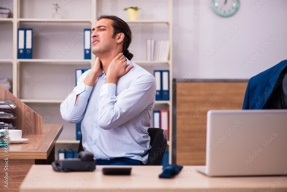 Young male employee suffering from osteochondrosis at workplace Young male employee suffering from osteochondrosis at workplace