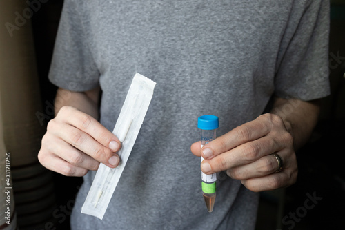 Man Holding Nasal Swab and Test Tube to Take a COVID-19 At-Home Test