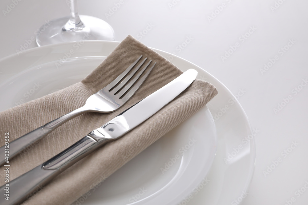 Elegant cutlery with napkin on white table, closeup Elegant cutlery with napkin on white table, closeup