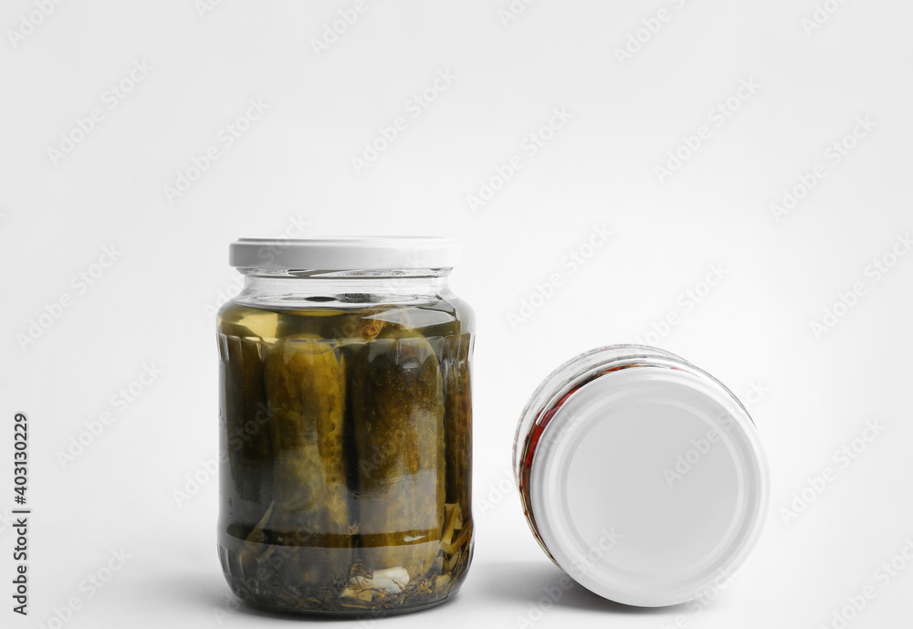 Glass jars with pickled cucumbers and bell peppers on white background Glass jars with pickled cucumbers and bell peppers on white background