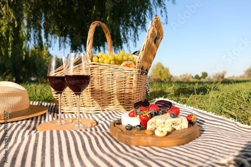 Fototapeta Naklejka Na Ścianę i Meble -  Red wine and different products for summer picnic served on blanket outdoors