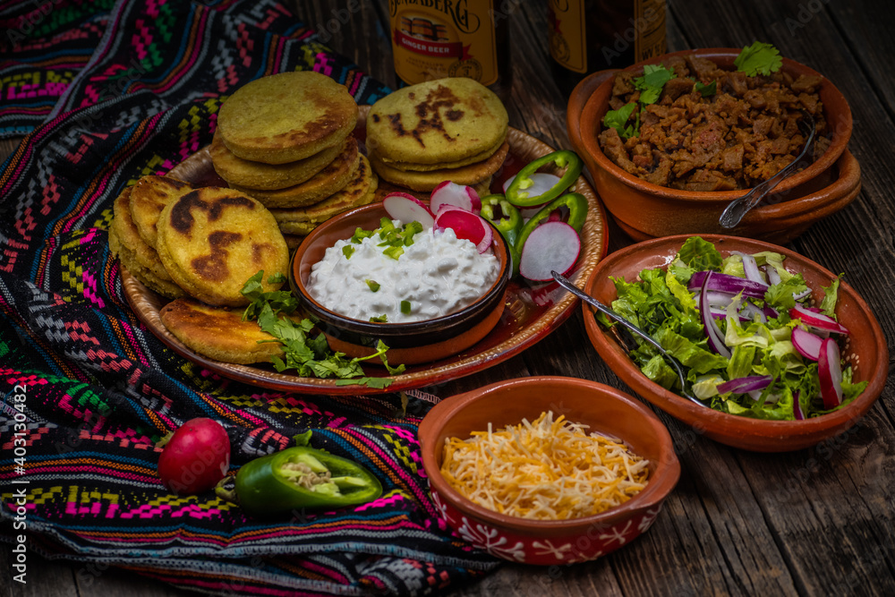 Fototapeta premium Traditional mexican gorditas with various vegetarian and vegan fillings: seitan, greens, cheese on wooden table