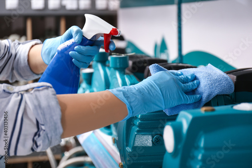 Woman cleaning water pump with rag and detergent in bathroom fixtures store, closeup