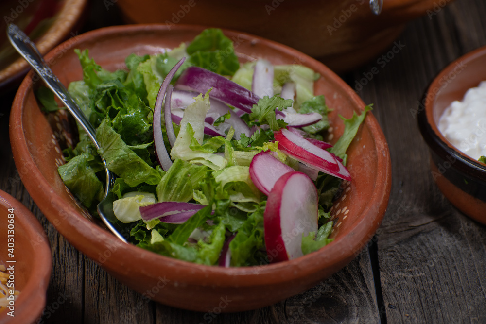 Letuce, onion and radish salad in clay bowl