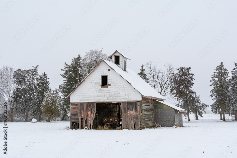 Old wooden barn in the snow on a foggy winter day.