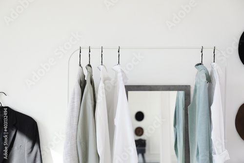 Rack with stylish clothes near mirror in dressing room