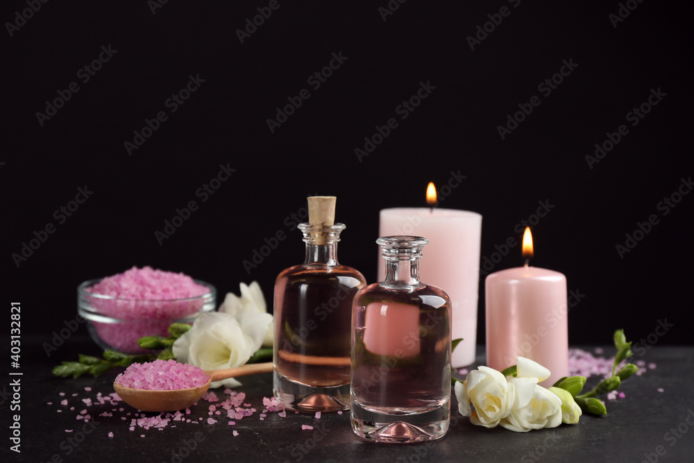 Beautiful spa composition with essential oil and candles on black table Beautiful spa composition with essential oil and candles on black table