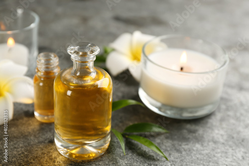 Beautiful spa composition with essential oil  candles and flowers on grey table  closeup