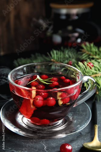 Tasty hot cranberry tea with rosemary and lemon on black table