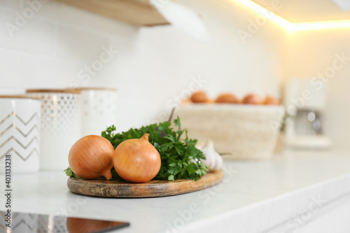 Fresh onions and parsley on white countertop in modern kitchen