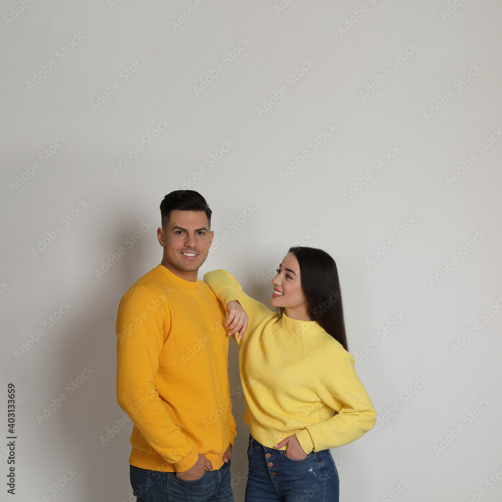 Happy couple wearing yellow warm sweaters on white background. Space for text Happy couple wearing yellow warm sweaters on white background. Space for text