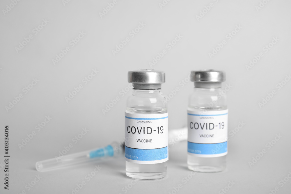 Vials with coronavirus vaccine and syringe on light background Vials with coronavirus vaccine and syringe on light background