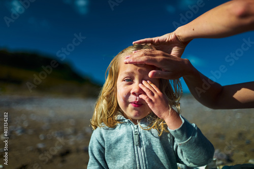 Fotografija Preschooler on the beach is having suncream applied