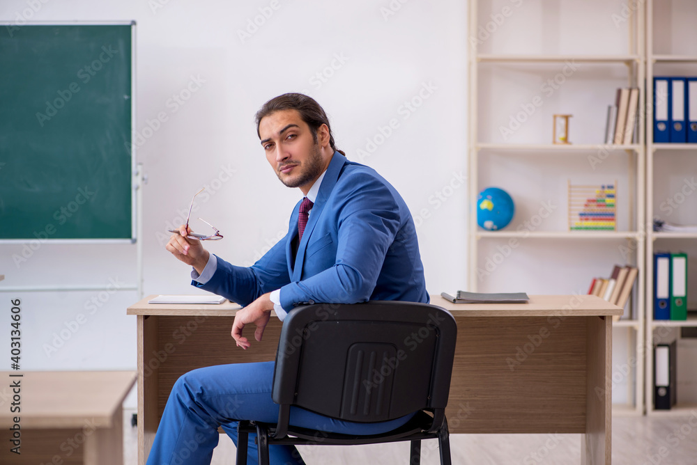 Young male teacher in suit in front of green board Young male teacher in suit in front of green board
