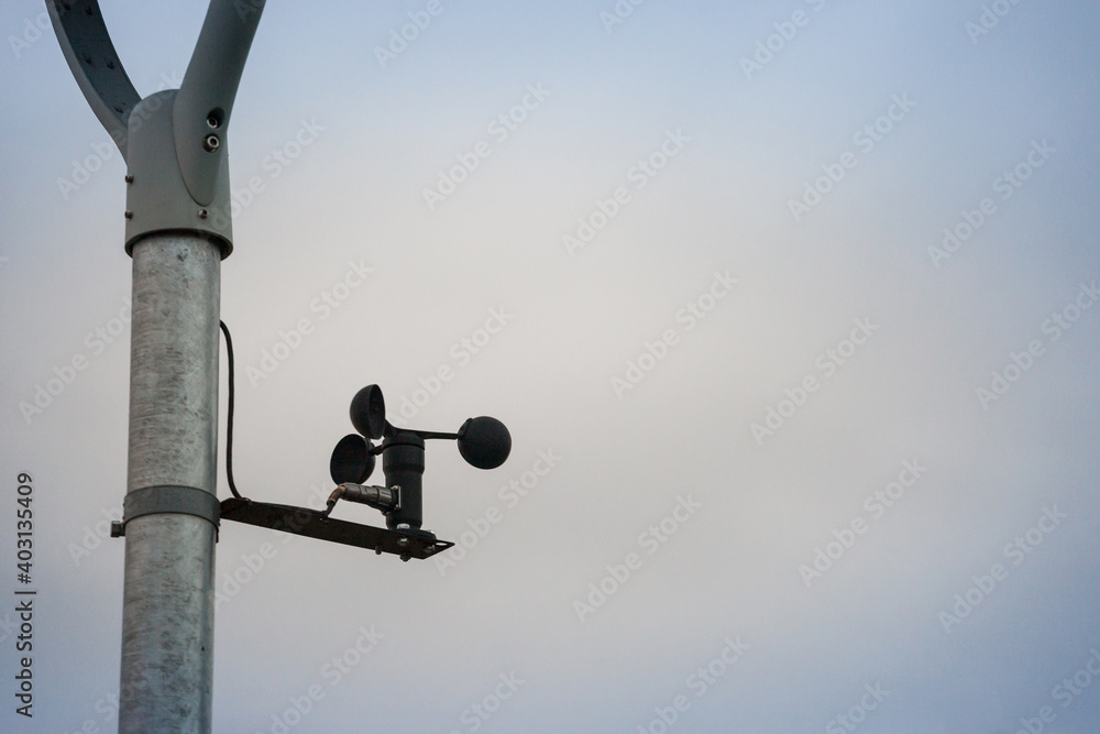 Anemometer spinning and turning in the wind in front of a grey cloudy weather. An anemometre is used in meteorology to measure the speed of wind Anemometer spinning and turning in the wind in front of a grey cloudy weather. An anemometre is used in meteorology to measure the speed of wind