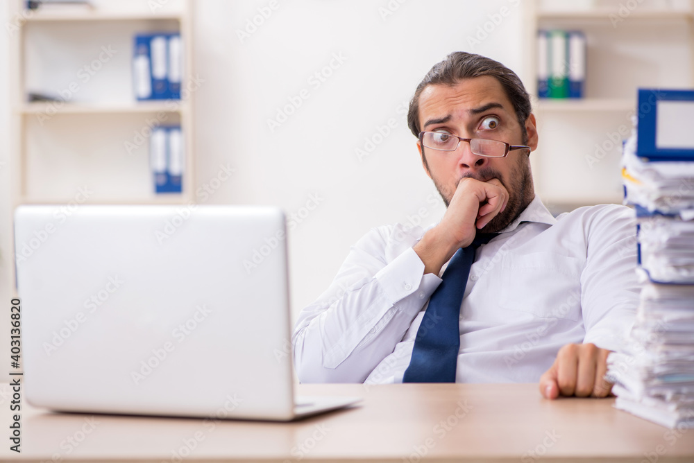 Young businessman unhappy with excessive work in the office Young businessman unhappy with excessive work in the office
