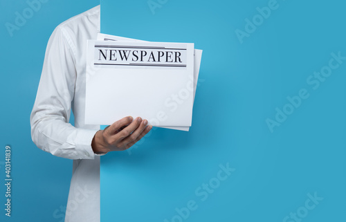Male holding blank business newspaper on blue background,copy space for text