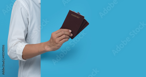 Male hand holding passport on blue background,copy space for text