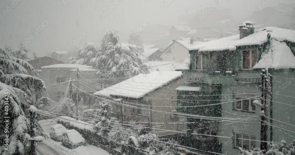 Heavy snow falling in the city with small houses Heavy snow falling in the city with small houses