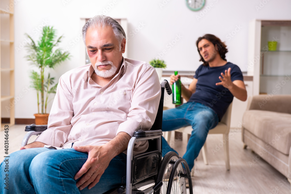 Old man in wheel-chair and young bad caregiver indoors - obrazy, fototapety, plakaty 