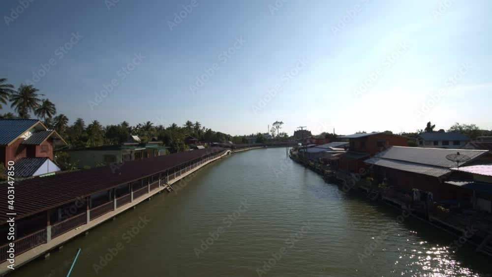 Calm river gently flowing through a village in Thailand on a bright sunny day Calm river gently flowing through a village in Thailand on a bright sunny day