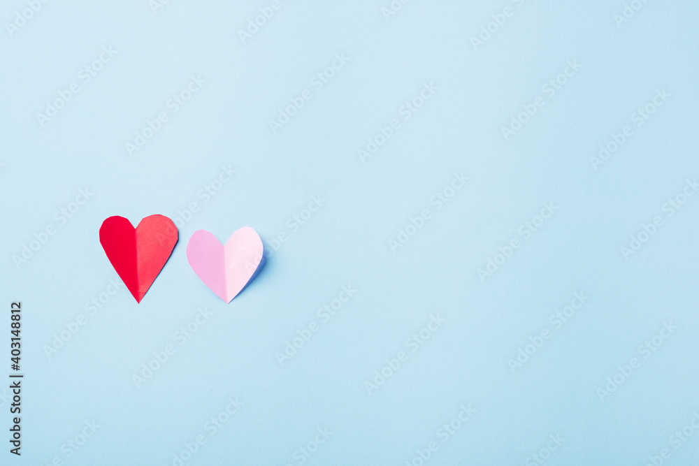 Valentines' day background. Beautiful red and pink paper hearts cut composition greeting card isolated on blue background with copy space, Symbol of love Top View from above