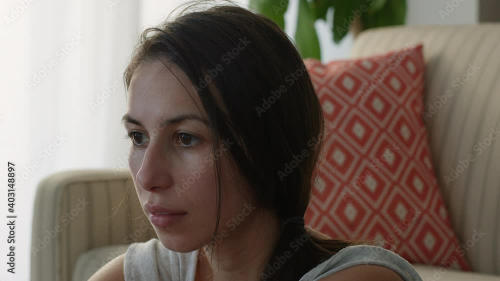 Woman signs to herself as she works from home on living room floor - close up on face Woman signs to herself as she works from home on living room floor - close up on face