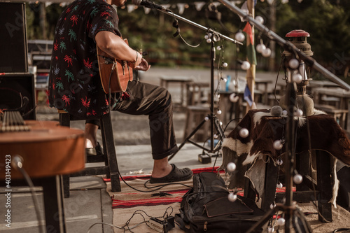 A musician wearing a Hawaiian shirt plays the guitar on stage at a music festival..Concert,mini concert and music festivals.