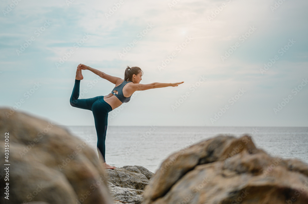 Woman training yoga on the beach in the morning.Yoga,fitness and healthy lifestyle concept Woman training yoga on the beach in the morning.Yoga,fitness and healthy lifestyle concept