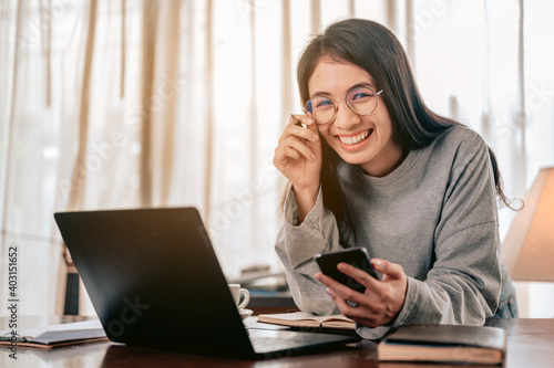 Portrait Happy woman working from home,She using smartphone chatting answer for customer.Work from home and covid19 concept