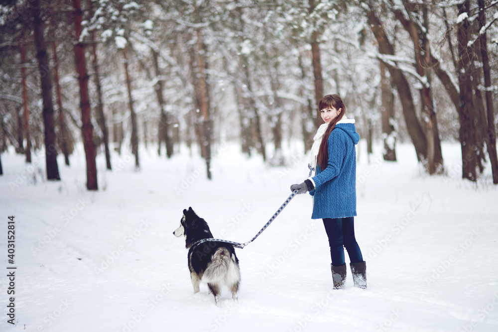 Girl walks with dog siberian husky in winter snowy forest Girl walks with dog siberian husky in winter snowy forest
